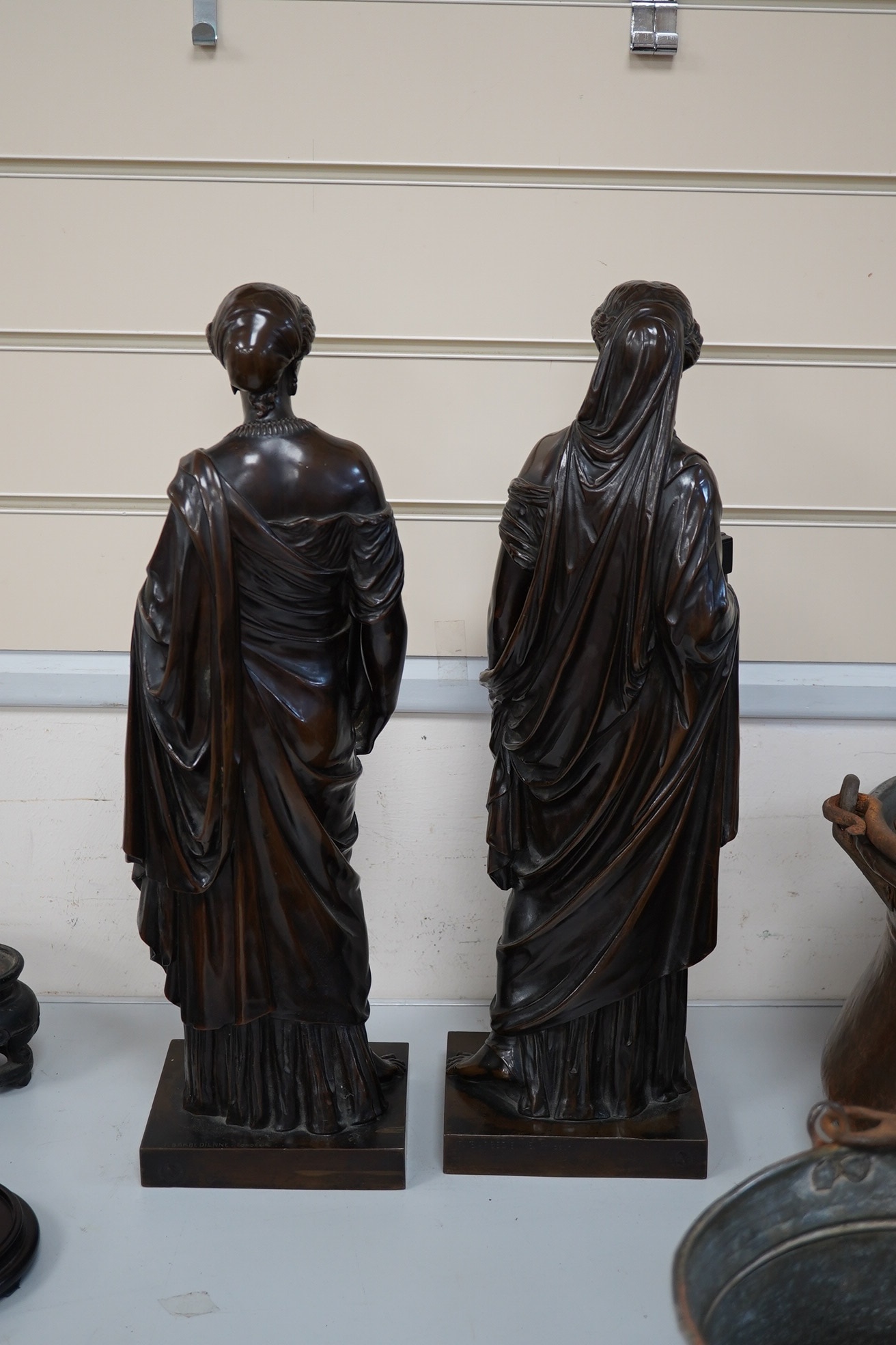 Eugene-Antoine Aizelin (French, 1820-1902). A pair of bronze classical robed figures of Pandora and Hebe, one holding a casket, the other a ewer and cup, having dark brown patination Height 50cm on square plinth base, si